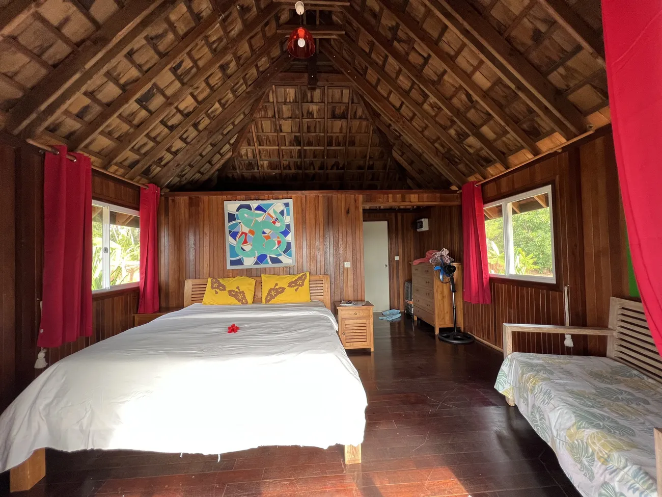 Intérieur de bungalow, charpente bois apparente, lit, déco polynésienne